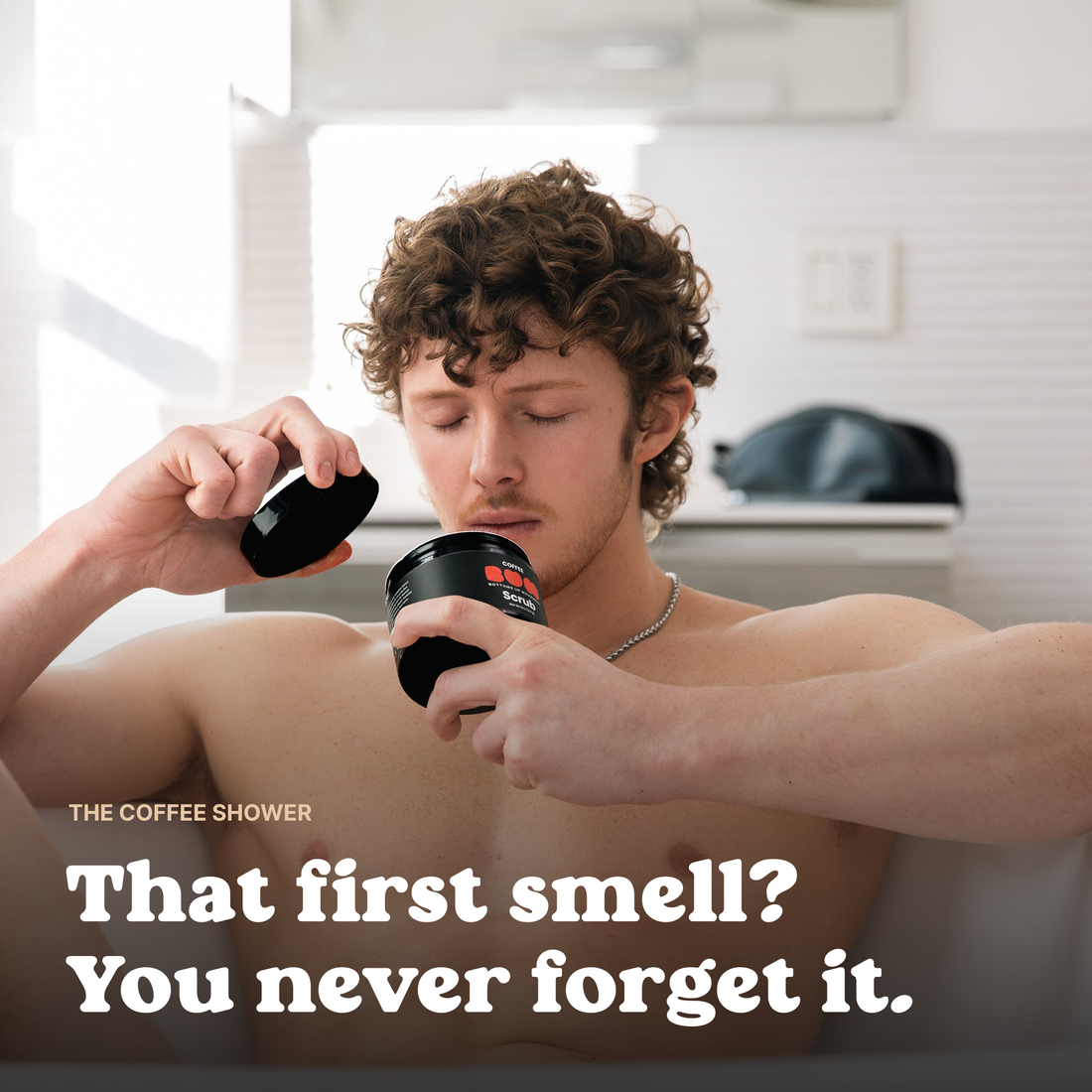 Man in the bath opening a jar of BUM Coffee Scrub and smelling the coffee aroma